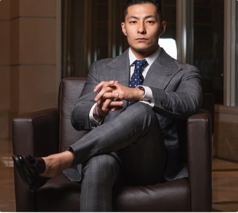 Retrato corporativo do advogado Bruno Hideki sentado em poltrona de couro