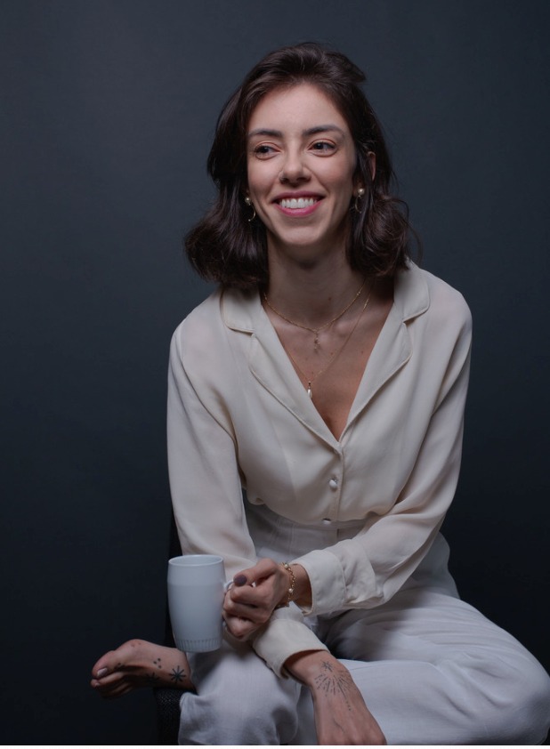 Retrato corporativo sentada com blazer claro em fundo escuro